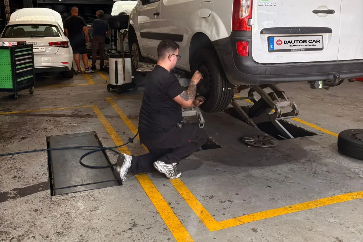 Mecánico revisando la rueda y los frenos de una furgoneta en el taller Dautos Car de Marbella